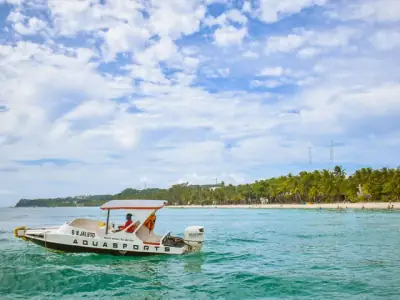 A bright summer scene showing a speedboat cruising near Boracay's white sand beach, Philippines.