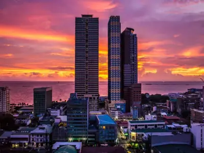 Stunning cityscape of Manila skyscrapers during a colorful sunset with sea view.