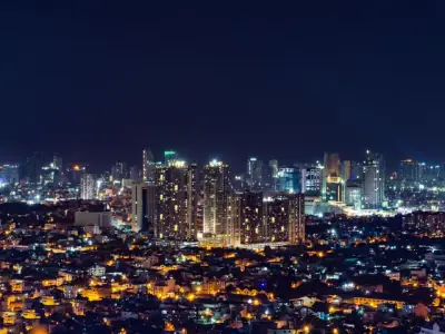 A stunning night view of the illuminated Manila skyline, showcasing modern urban architecture.