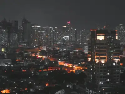 A stunning aerial view of Manila cityscape at night featuring brightly lit skyscrapers and urban glow.