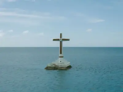 Aerial view of the iconic Sunken Cemetery Cross in Camiguin, captured against the serene ocean backdrop.