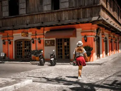 Woman walking on cobblestoned street in Vigan, Philippines, with vintage architecture.