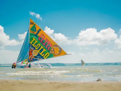 Colorful sailboat on the beach in Iloilo City, Philippines under clear skies.