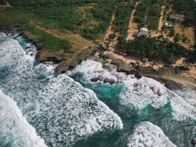 Stunning aerial photo showcasing Bolinao's rugged coastline with crashing waves and lush greenery.