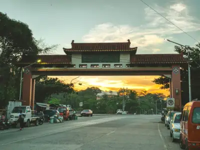 Scenic view of Dumaguete City's Chinese archway during sunset with cars lining the street.