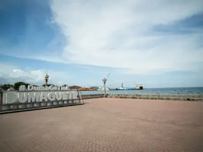 Scenic view of Dumaguete City harbor with iconic sign and ocean backdrop on a sunny day.