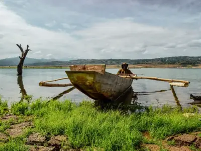 A traditional fisherman in an outrigger boat on Pantabangan Lake with scenic mountainous backdrop.