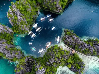 Stunning aerial shot of boats in a turquoise lagoon surrounded by rock formations in El Nido, Palawan, Philippines.