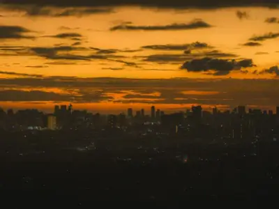 Capture of Antipolo city skyline silhouetted against a warm, orange sunset.